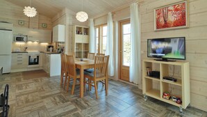 Una cocina moderna con armarios de madera, una mesa de comedor con sillas, un televisor sobre un mueble de madera y un cuadro en la pared.