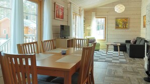 Una habitación con paneles de madera, una mesa de comedor, sillas, un sofá y un televisor.