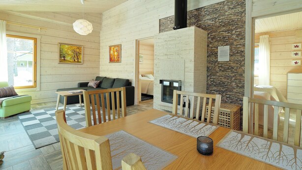 Un interior moderno con techo de madera, chimenea y zona de comedor con alfombra a cuadros.