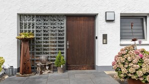 Un bâtiment doté d’une grande porte en bois, d’un portail en métal et d’une fenêtre agrémentée d’un élément décoratif.
