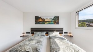 Un lit double avec une tête de lit, des tables de chevet et un tableau accroché au mur.