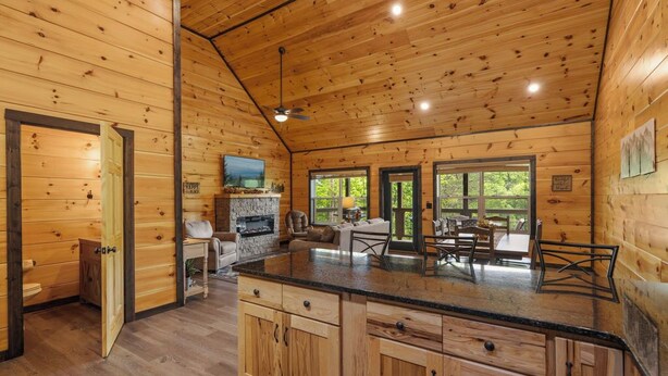 A wooden cabin interior with a kitchen, dining area, and a fireplace. - Heavenly Splash: Dive Into Paradise (Sevierville)