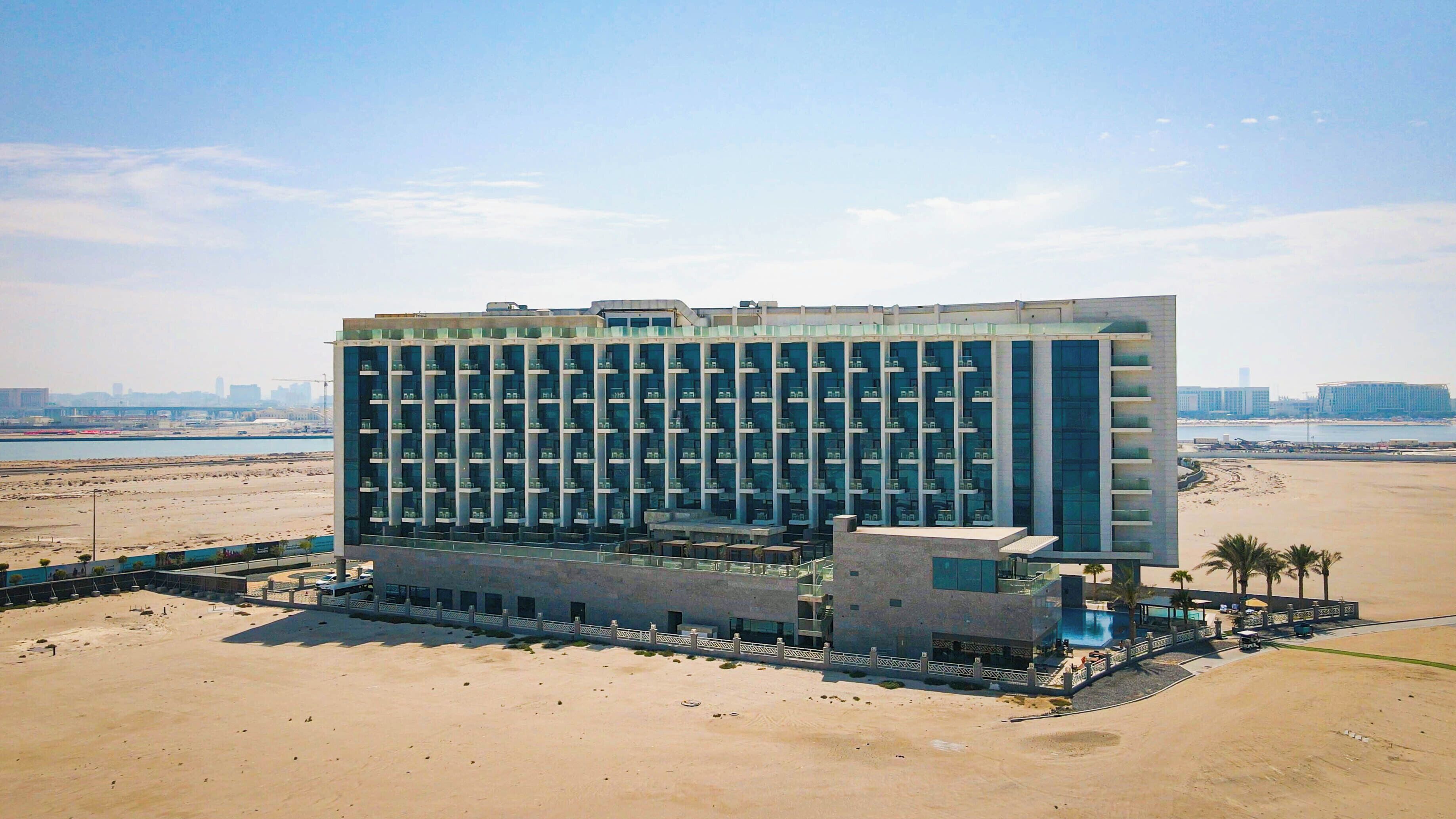 A modern hotel with a central courtyard, multiple floors, and a beach view.