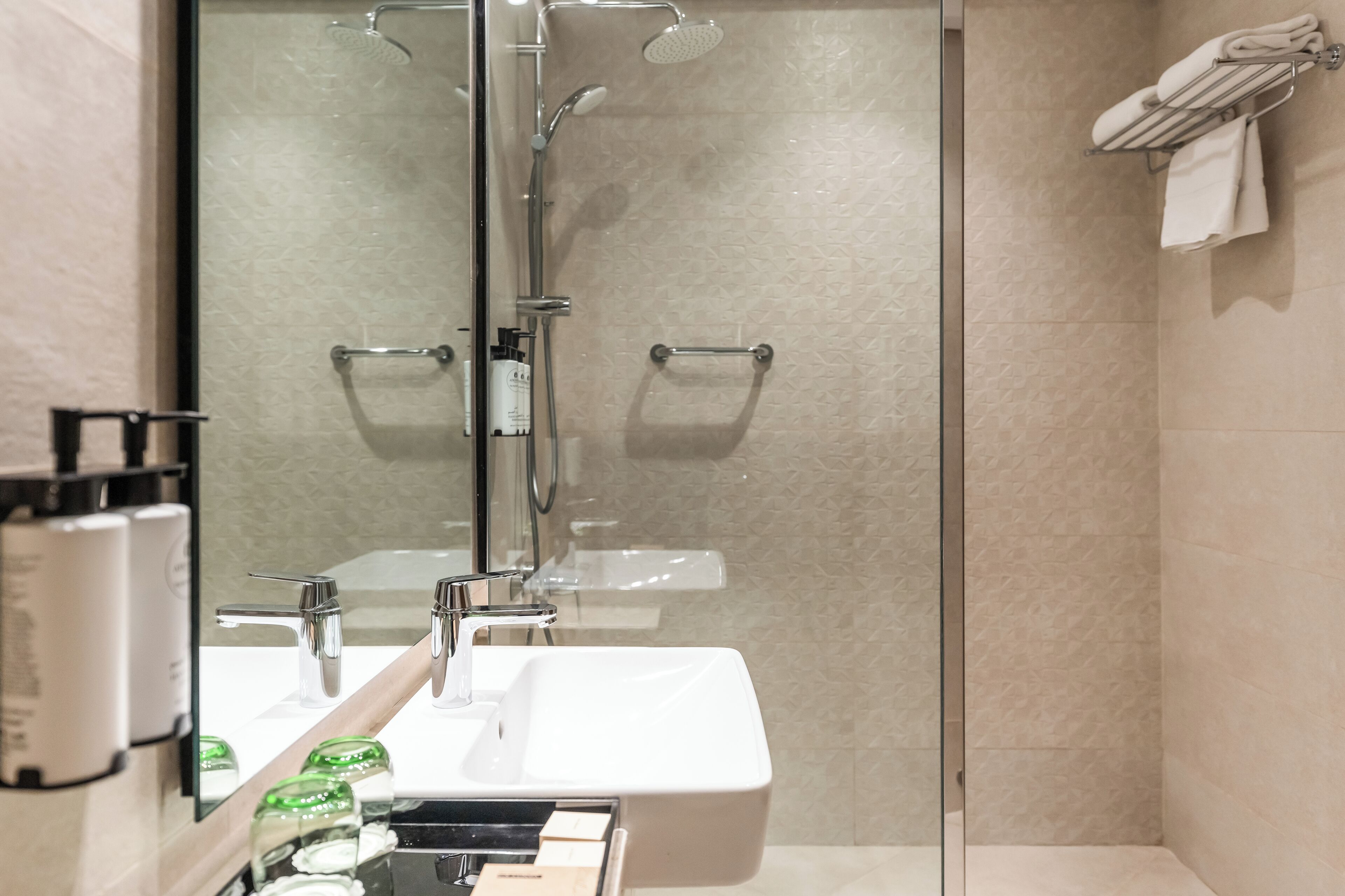 Une salle de bain moderne avec une douche à parois de verre, un lavabo blanc et un porte-serviettes.