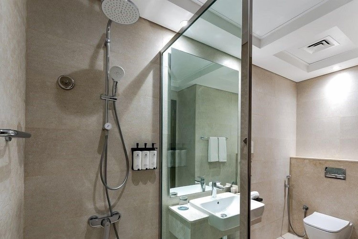 Un baño moderno con cabina de ducha de vidrio, un lavabo e inodoro.