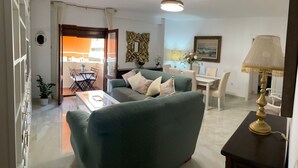 Een woonkamer met een bank, een eettafel en een lamp.