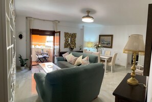 A living room with a sofa, a dining table, and a lamp.