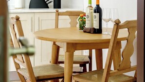 A wooden dining table with four chairs, a bottle of wine, and two wine glasses on the table. - CASA DAS COLMEIAS A haven of tranquillity, where nature reveals all its beauty. (Distrito de Évora)