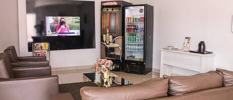 Un salon moderne doté d’un téléviseur à écran plat, d’un mini-bar, d’un coin salon avec des canapés en cuir et d’un vase décoratif.