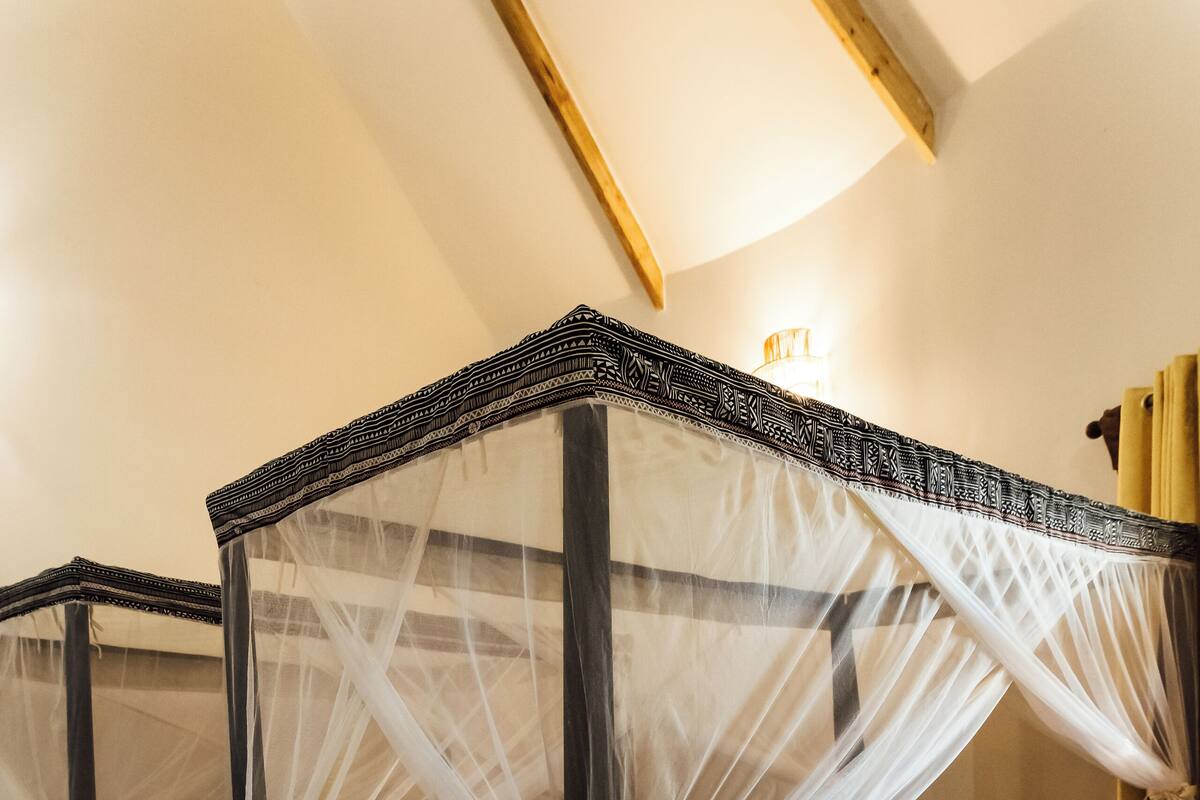 A bedroom with two four-poster beds, each with a canopy, and a wooden floor.