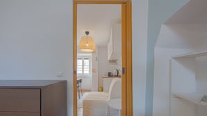 Un couloir étroit mène à une chambre qui contient un lit, une chaise et un coin cuisine.