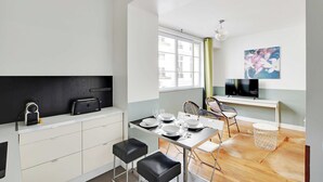 A modern kitchen with a dining area, a TV, and a window with curtains. - Charming Apartment - 1br-6p - Sentier (Paris)