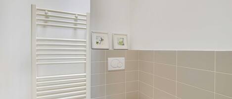 A bathroom with a white toilet, a towel rack, and two framed pictures on the wall.