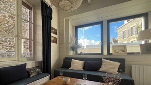 Un salon chaleureux avec un mur en pierre, un canapé bleu foncé, une table basse en bois et une vue sur l’extérieur.