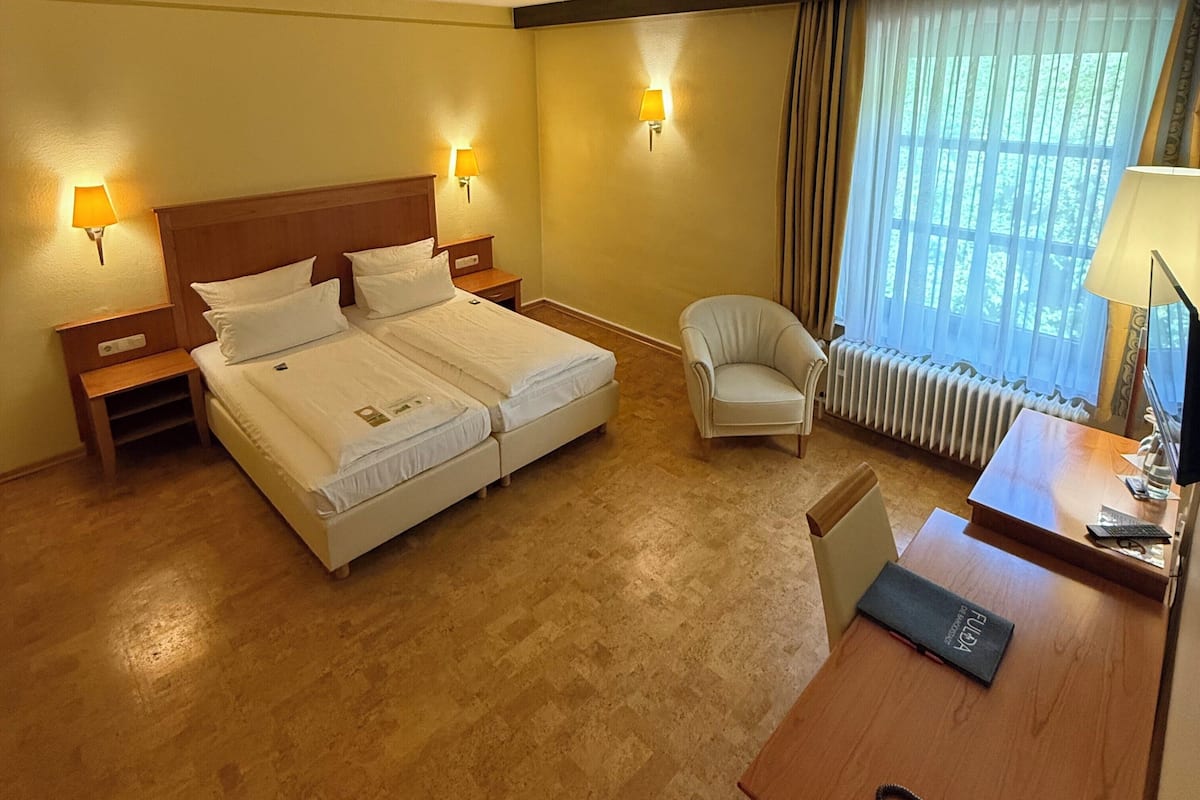 A hotel room with a double bed, a desk with a telephone, and a chair.