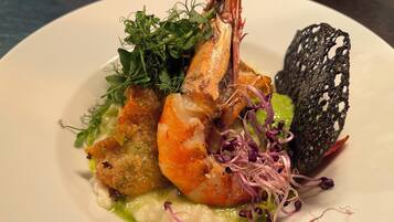 Un plato con camarones, vegetales verdes y una especie de pan.