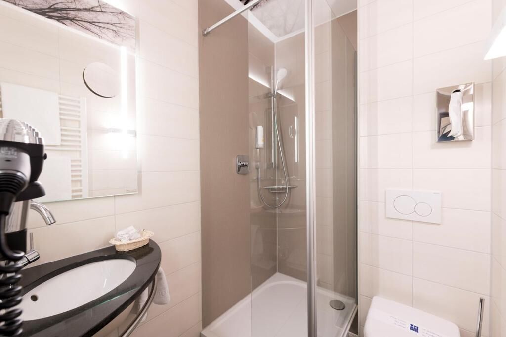 Un baño moderno con ducha acristalada, lavabo negro y retrete.