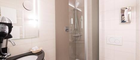 Un baño moderno con ducha acristalada, lavabo negro y retrete.