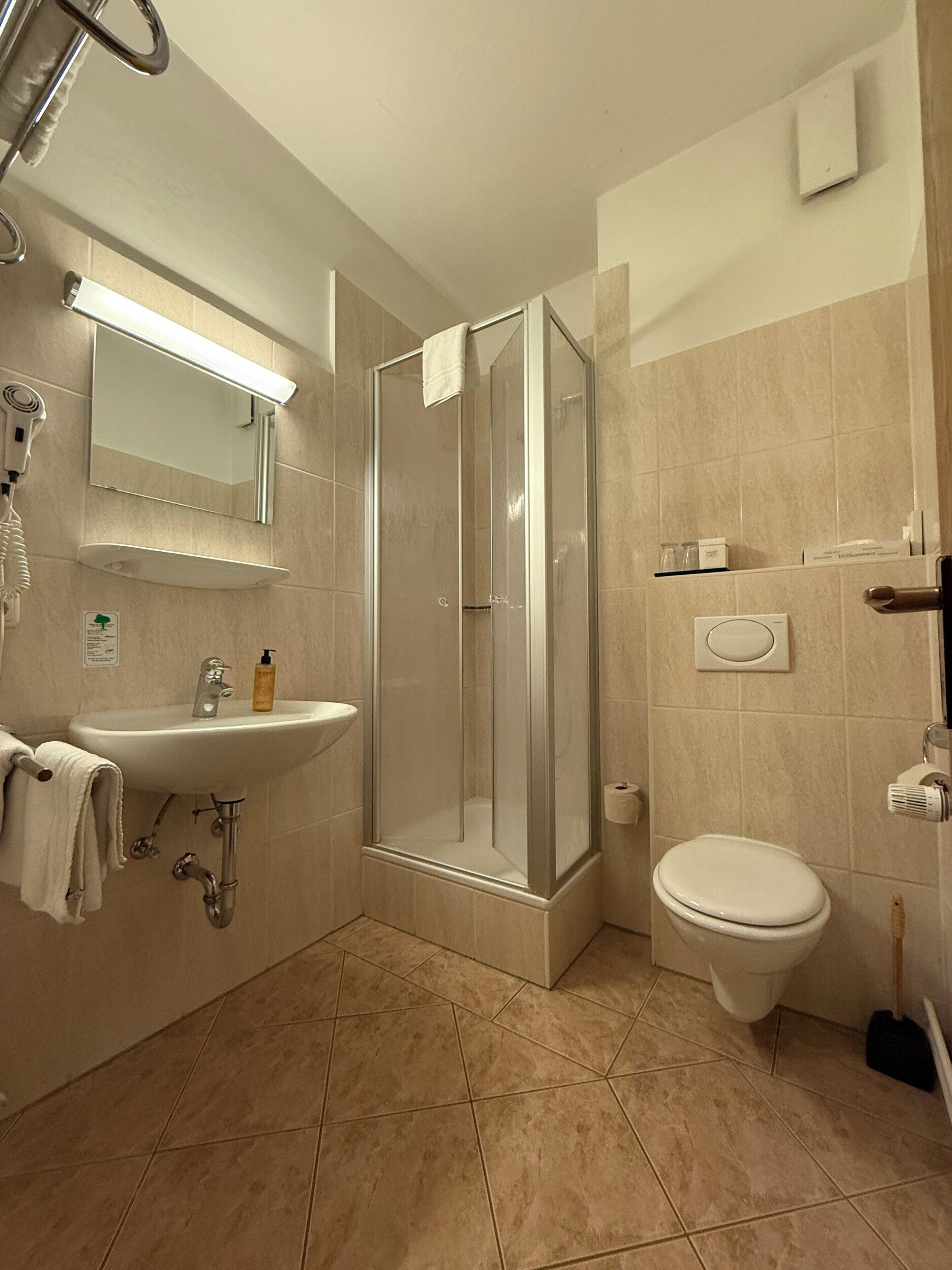 A modern bathroom with a glass-enclosed shower, a sink, and a toilet.