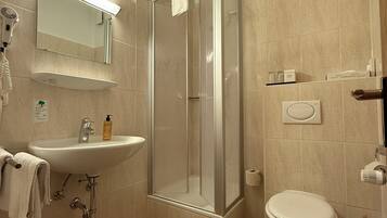Un baño moderno con ducha de vidrio, lavamanos e inodoro.