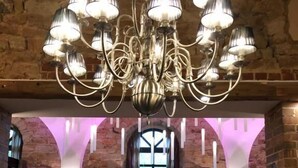 A restaurant with a chandelier, stone walls, and a bar area. - Hotel-Restaurant Bachmühle (Fulda)