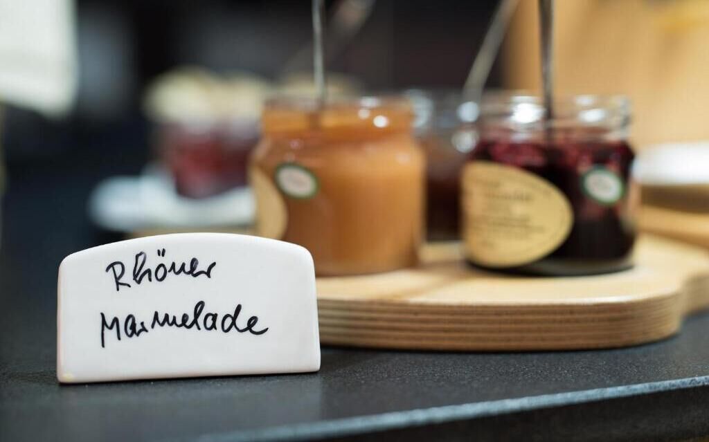 Un cartel que dice 'Rhöner Marmelade', con botes de mermelada al fondo.