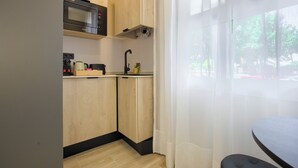 Una cocina compacta con armarios de madera, un microondas y un lavabo.