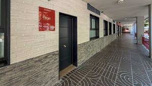Un pasillo con piso estampado, un letrero rojo y una puerta negra.