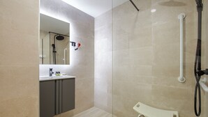 Un baño moderno con ducha, tocador con espejo y banco.