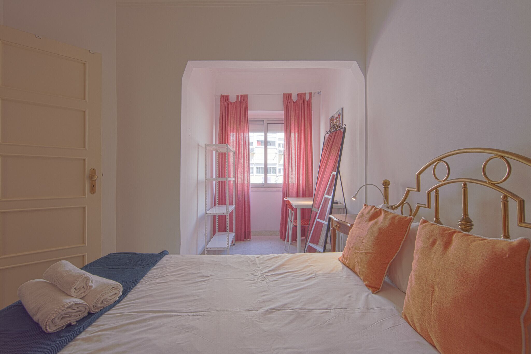 Une chambre à coucher avec un lit, des oreillers, une échelle, une chaise et une fenêtre avec des rideaux.