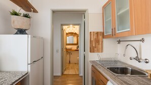 A kitchen with a refrigerator, sink, wooden cabinets, and a countertop. - Cascais Ocean View by Homing (Cascais)