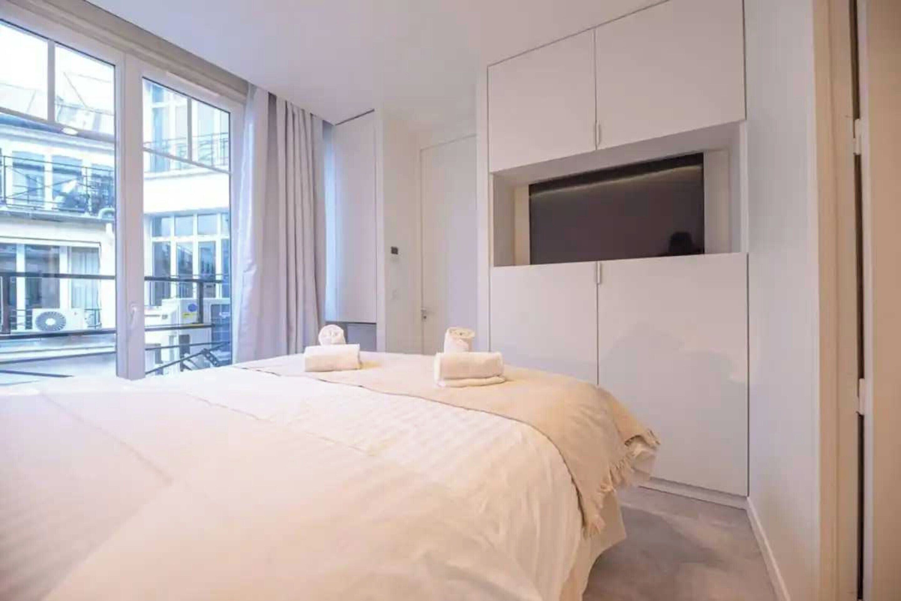 Ein Hotelzimmer mit einem großen Bett, einem an der Wand befestigten Fernseher und einer Glastür zum Außenbereich.