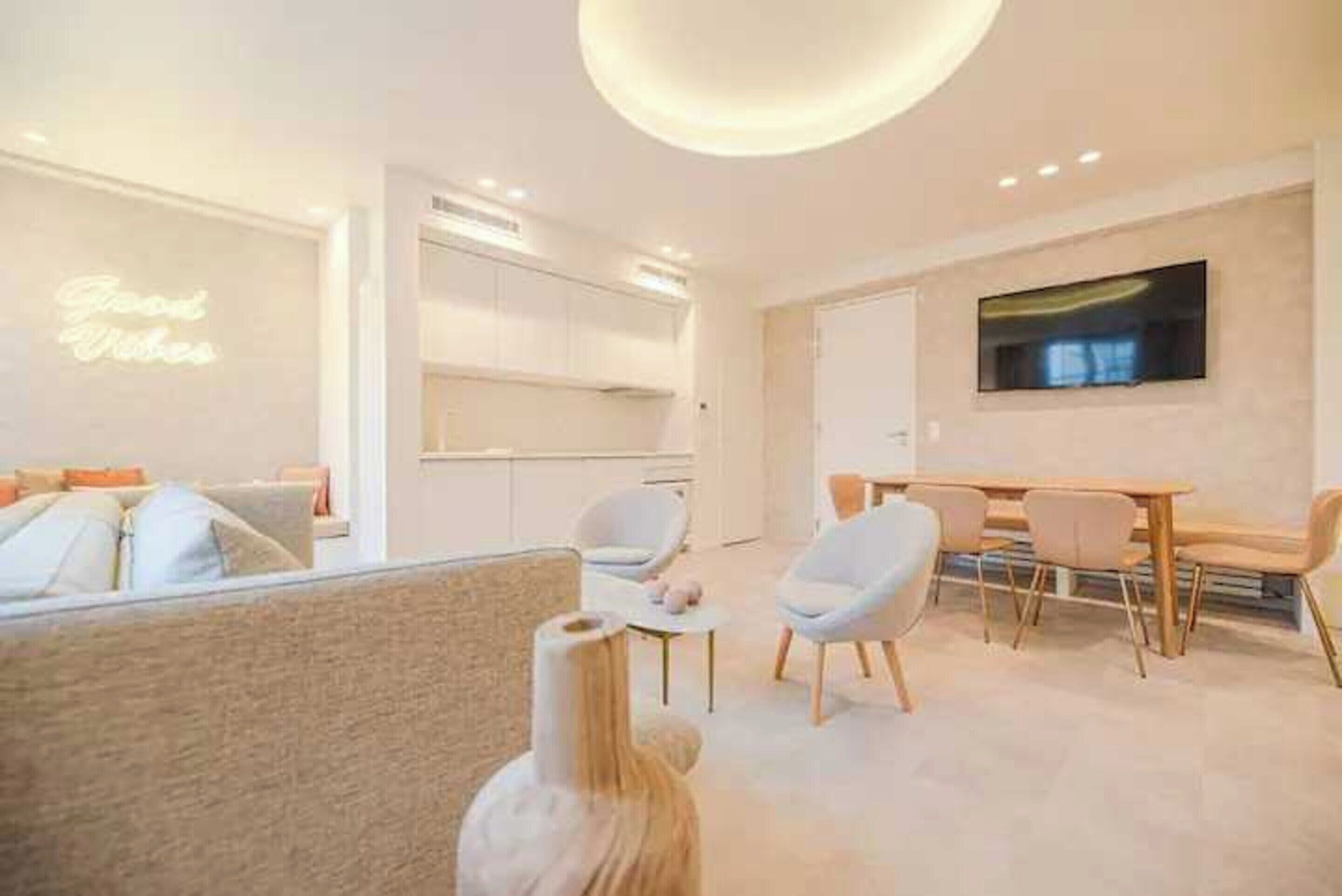 Una sala moderna con un sofá, un comedor con mesa y sillas, y una cocina al fondo.