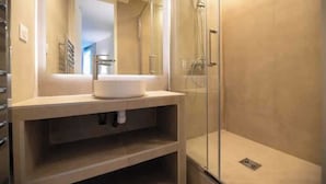 Une salle de bain moderne avec une douche à parois de verre, un lavabo avec un miroir au-dessus et un porte-serviettes sur le côté gauche.