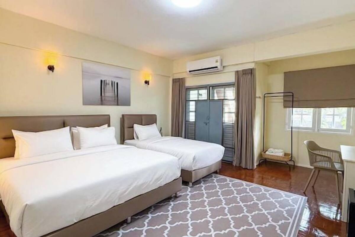 A hotel room with two beds, a desk, and a chair.