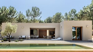 A modern house with a pool, outdoor seating, and a view of trees. - Melides Premium Villa by Homing (Grandola)