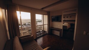 A hotel room with a large window, a sofa, a TV, and a bed. - Salvatori Hotel (Telemaco Borba)