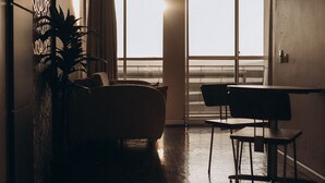 A spacious room with a large window, a sofa, a dining table, and a potted plant. - Salvatori Hotel (Telemaco Borba)