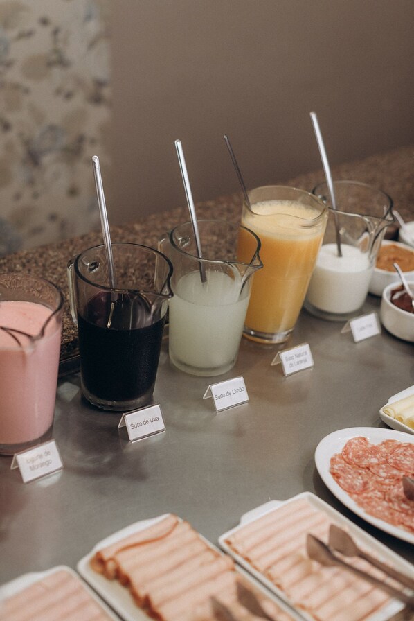 A buffet with various food and drink options, including labeled containers of different sauces and a selection of meats. - Salvatori Hotel (Telemaco Borba)