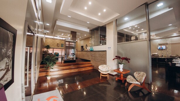 A modern hotel lobby with a reception desk, seating area, and a staircase leading to upper floors. - Salvatori Hotel (Telemaco Borba)