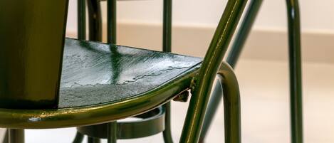 A close-up of a chair with a metallic frame and a green seat.