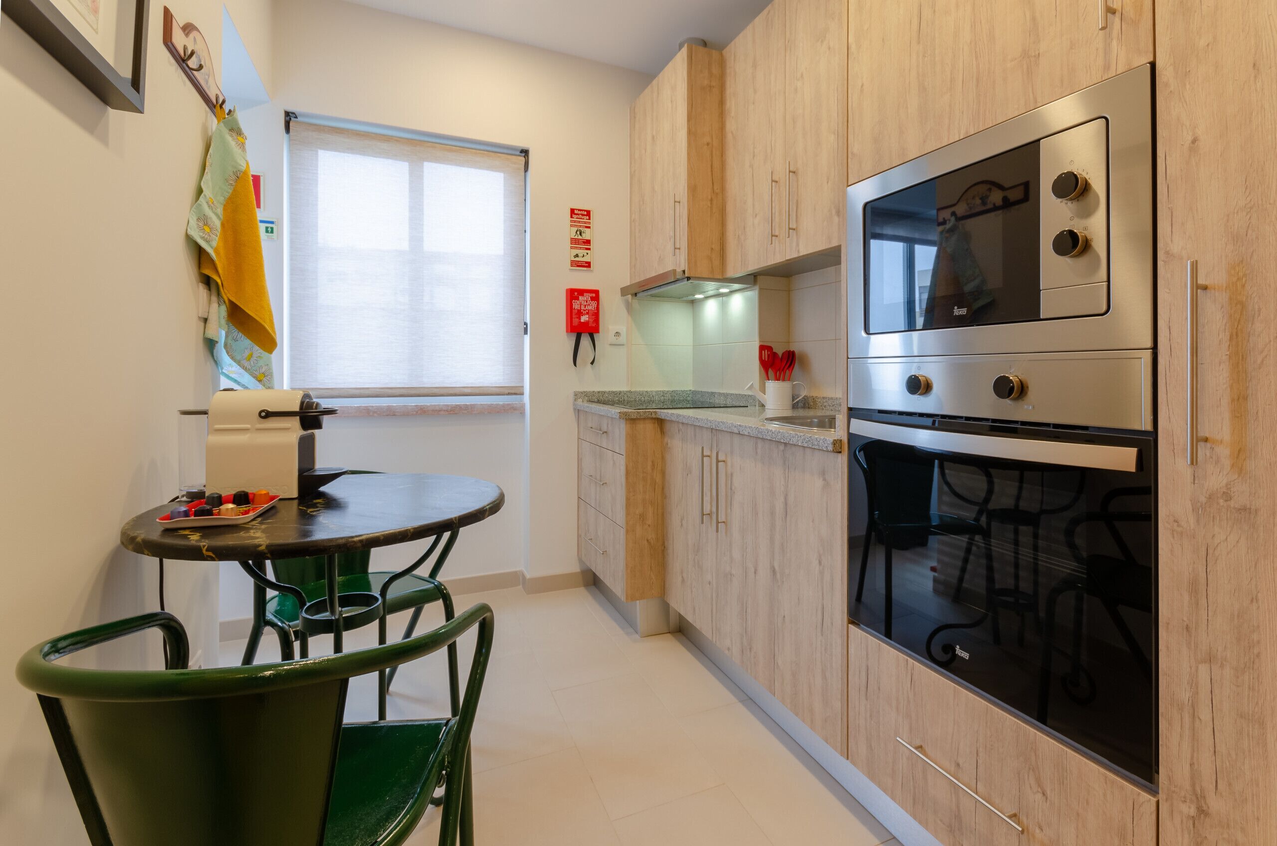 A compact kitchen with wooden cabinets, a built-in oven, and a small dining area with a table and chairs.