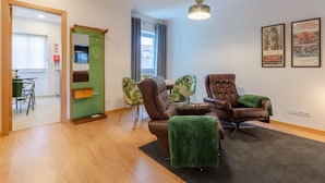 A modern living room with a brown leather sofa, green armchairs, and a dining table. - Setubal Boutique Apartments III (Setubal)