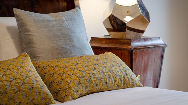 A bed with two pillows, a wooden headboard, and a lamp on a wooden nightstand. - Setubal Boutique Apartments III (Setubal)