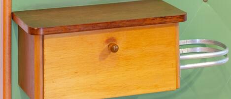 Un armario de madera con un cajón, un anillo metálico y una pared verde.
