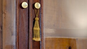 A wooden door with two brass knobs and a gold tassel hanging from the center. - Setubal Boutique Apartments III (Setubal)