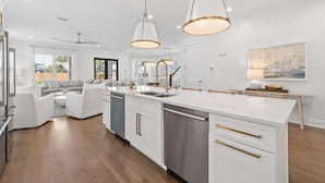 A modern kitchen with white cabinetry, stainless steel appliances, and pendant lighting.