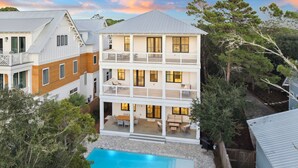 A two-story house with a swimming pool, wooden deck, and a fenced yard.
