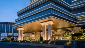 A modern building with a glass facade, large columns, and a well-lit entrance. - LUNGCHUEN INTERNATIONAL HOTEL (Dongguan)