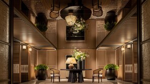 Eine moderne Lobby mit einem runden Tisch, zwei Stühlen, einer Blumenvase und Topfpflanzen.